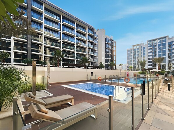 Un hôtel moderne doté d’une piscine sur le toit, de nombreux balcons et d’un aménagement paysager luxuriant.