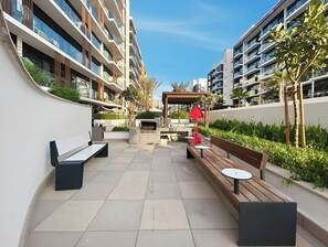 Un espace extérieur moderne, aménagé en patio, avec des bancs, une petite table et un barbecue.