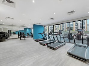 Une salle de sport moderne équipée de tapis de course, de vélos d’exercice et d’appareils de musculation.