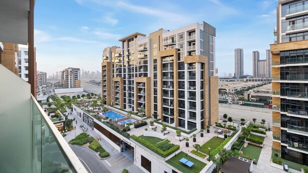 A modern apartment building with multiple balconies, a rooftop pool, and landscaped gardens. - Chic Modern Studio in Meydan (Dubai)