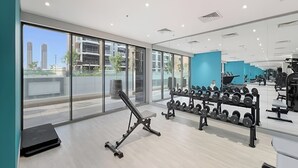 A modern gym with large windows, weight racks, and exercise equipment. - Chic Modern Studio in Meydan (Dubai)