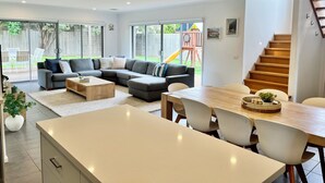 En moderne stue med en modulsofa, et spisebord med stole og et køkkenområde.