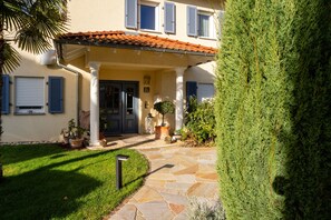 A building with a stone pathway leading to a dark door, potted plants, and a well-maintained lawn. - Apartment 'Fewo Luino' with Balcony and Wi-Fi (Gengenbach)