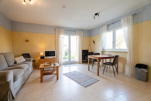 Een woonkamer met een bank, televisie, tafel, stoelen en een tv-meubel.