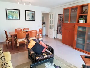 A living room with a sofa, a dining table with chairs, a cabinet, and two framed pictures on the wall. - "Cal Port" - 1st Sea Line - Beach - WiFi (Blanes)