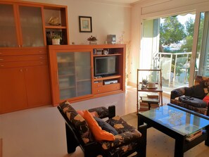 A living room with a sofa, a glass coffee table, a television, and a cabinet with glass doors. - "Cal Port" - 1st Sea Line - Beach - WiFi (Blanes)