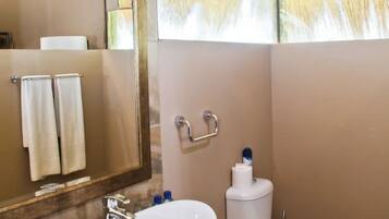 Un baño con un espejo grande, un lavamanos sobre encimera, un inodoro y un perchero para toallas.