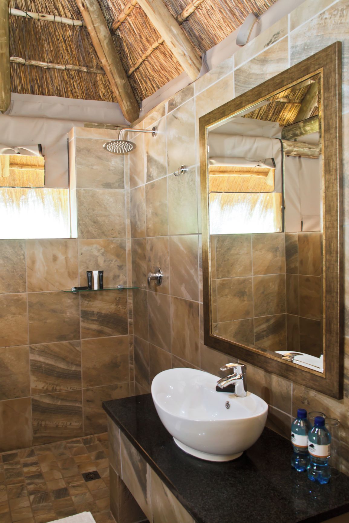 A bathroom with a large mirror, a white sink, and a shower.