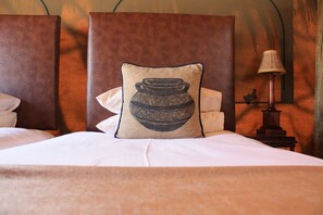 A neatly made bed with a pillow featuring a traditional pottery design, a lamp on a bedside table, and a headboard.