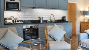 Una cucina moderna con mobili azzurri, forno integrato e tavolino in vetro.