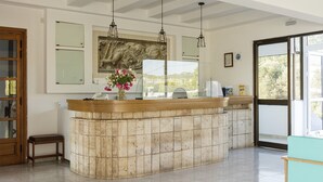 A reception area with a marble counter, a wooden bench, a vase of flowers, and a large window with a view. - Apartment in A Hotel 'Double Room No 2' with Shared Pool, Wi-Fi and Air Conditioning (Faliraki)
