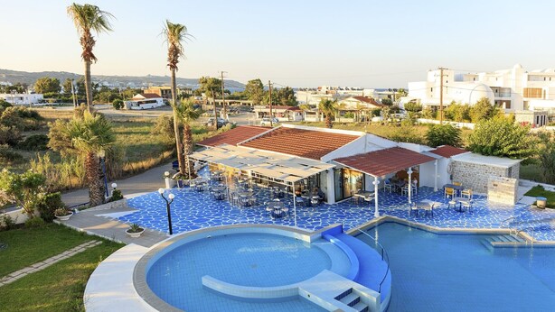 Ein Pool mit Sonnenterrasse, umgeben von einem Gebäude mit Außenbestuhlung.