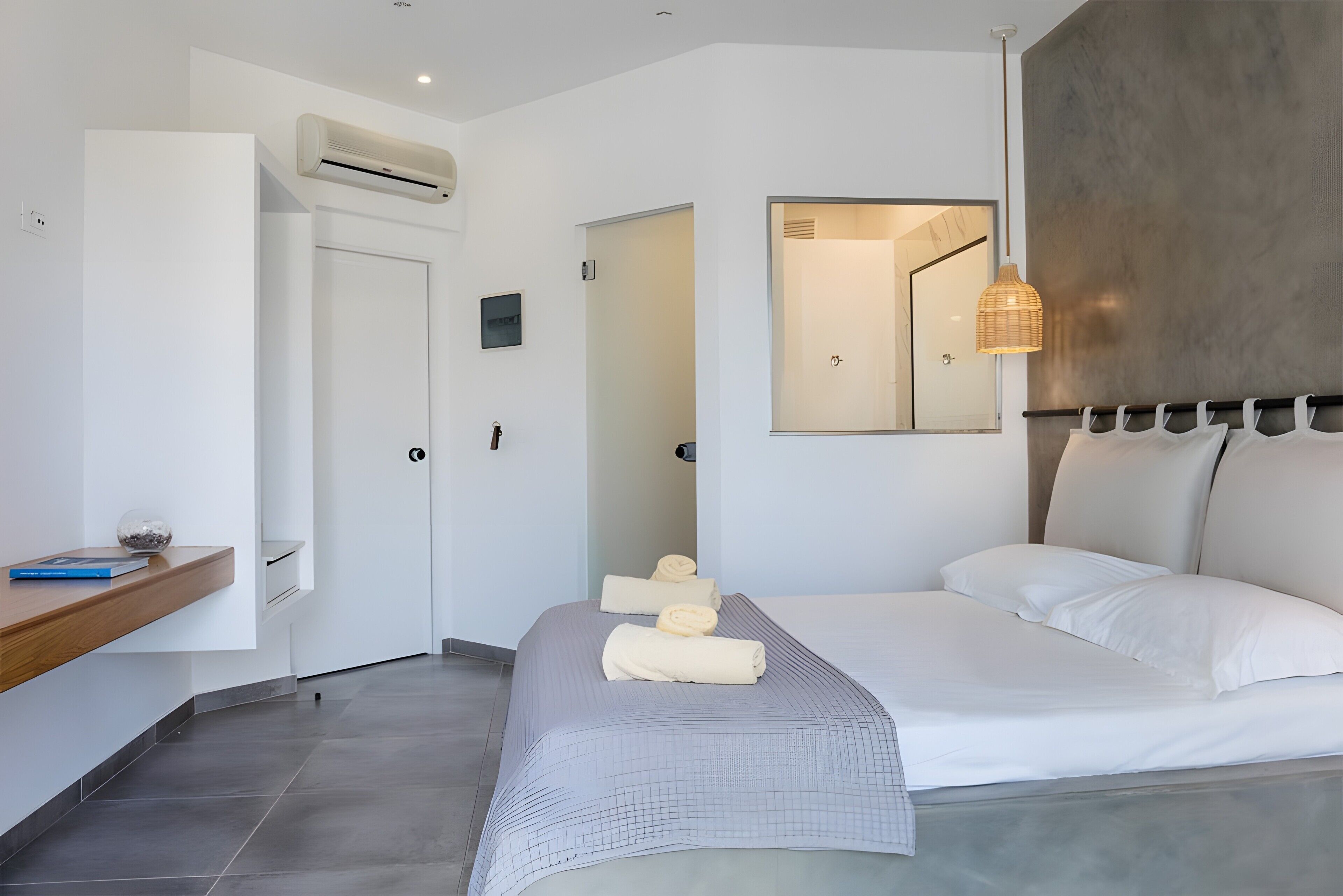 Un dormitorio moderno con una cama, una mesita de noche, un espejo y un aire acondicionado.
