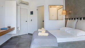 Ein modernes Schlafzimmer mit Bett, Nachttisch, Spiegel und Klimaanlage.