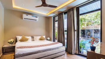 Un dormitorio con una cama grande, un equipo de aire acondicionado, un ventilador de techo y vistas a una cascada.