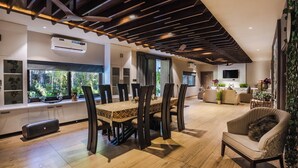 A spacious living area with a dining table and chairs, a sofa, and a TV. - The Out House Pushkar (Pushkar)