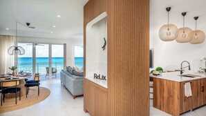 Una cocina moderna con una isla de madera, un comedor con vistas al mar y un ventanal grande.