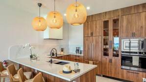 Una cocina moderna con una isla central, armarios de madera e iluminación colgante.