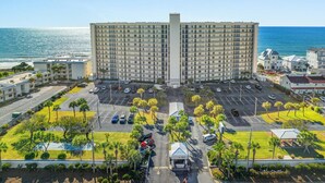 A large hotel with multiple floors, a parking lot, and a view of the ocean. - Beachfront Comfort | 3BR/3BA | 4th Floor | Quiet East End **BEACH CHAIRS (Panama City Beach)