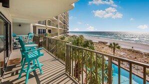 A balcony with turquoise chairs and a pool overlooking a beach. - Beachfront Comfort | 3BR/3BA | 4th Floor | Quiet East End **BEACH CHAIRS (Panama City Beach)
