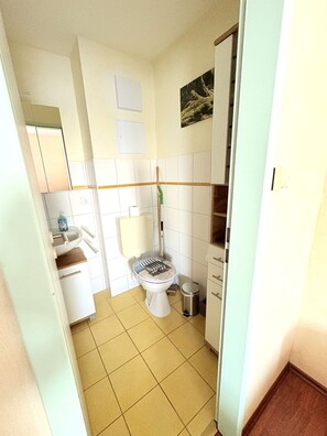 Ein kleines Badezimmer mit Toilette, Waschbecken und Mülleimer.