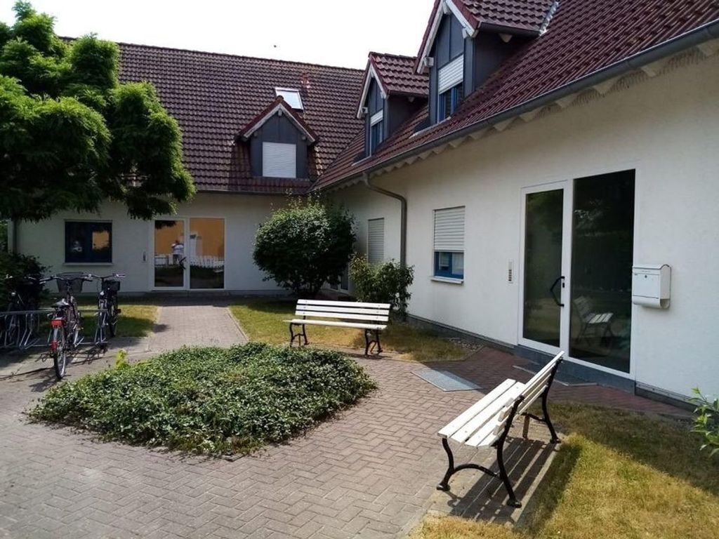 Un patio con un camino empedrado, un banco y bicicletas.