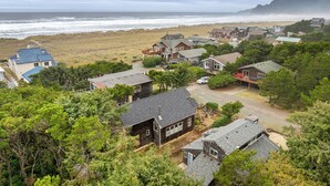 Zona residencial costera con casas, una playa y un paisaje montañoso al fondo.