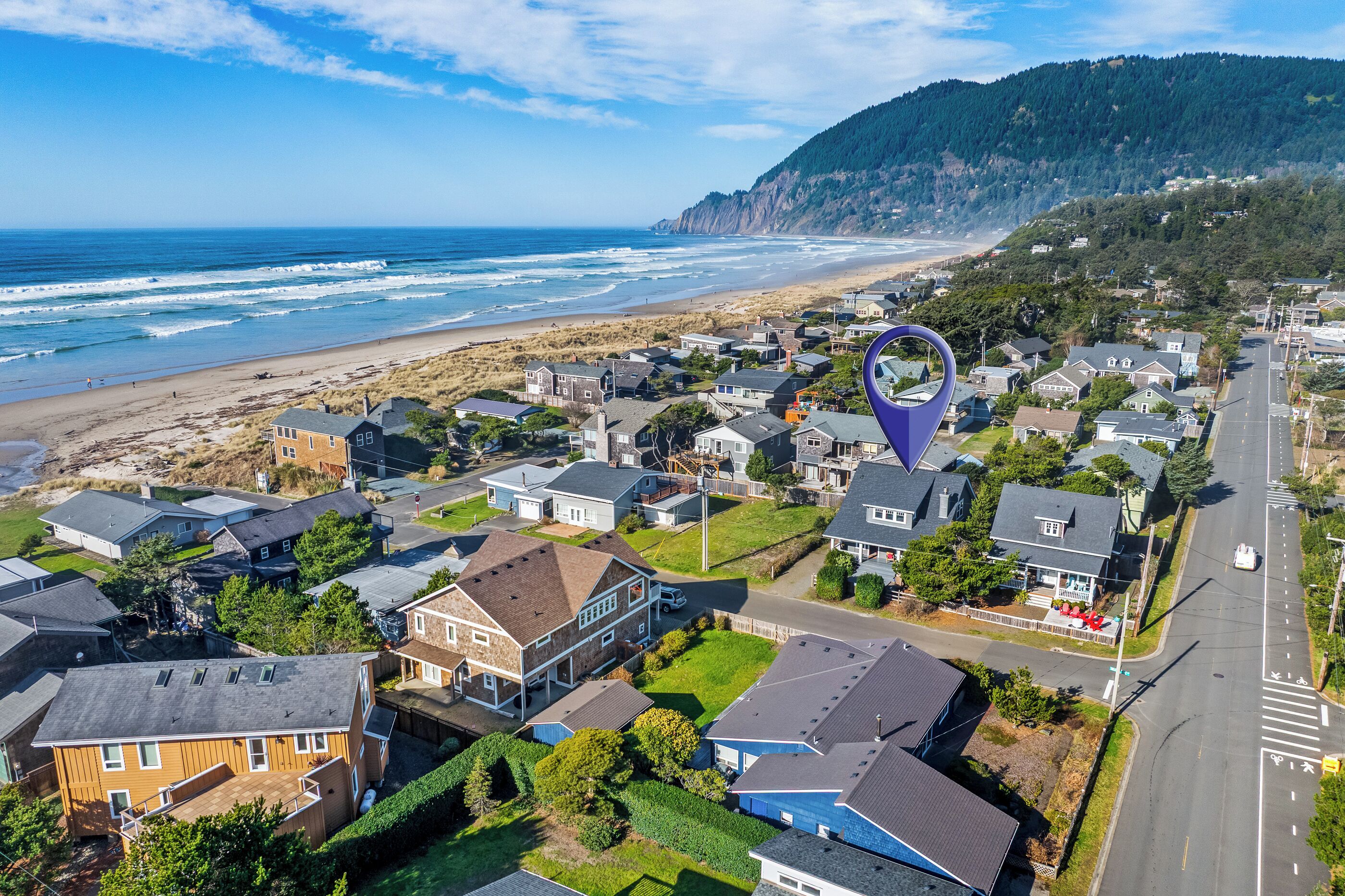 A residential area with houses, a beach, and a forested hill.