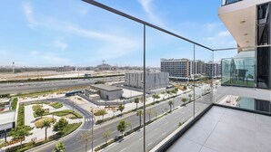 Un edificio moderno con fachada de vidrio que da a una zona urbana bien cuidada, con calles y otros edificios.