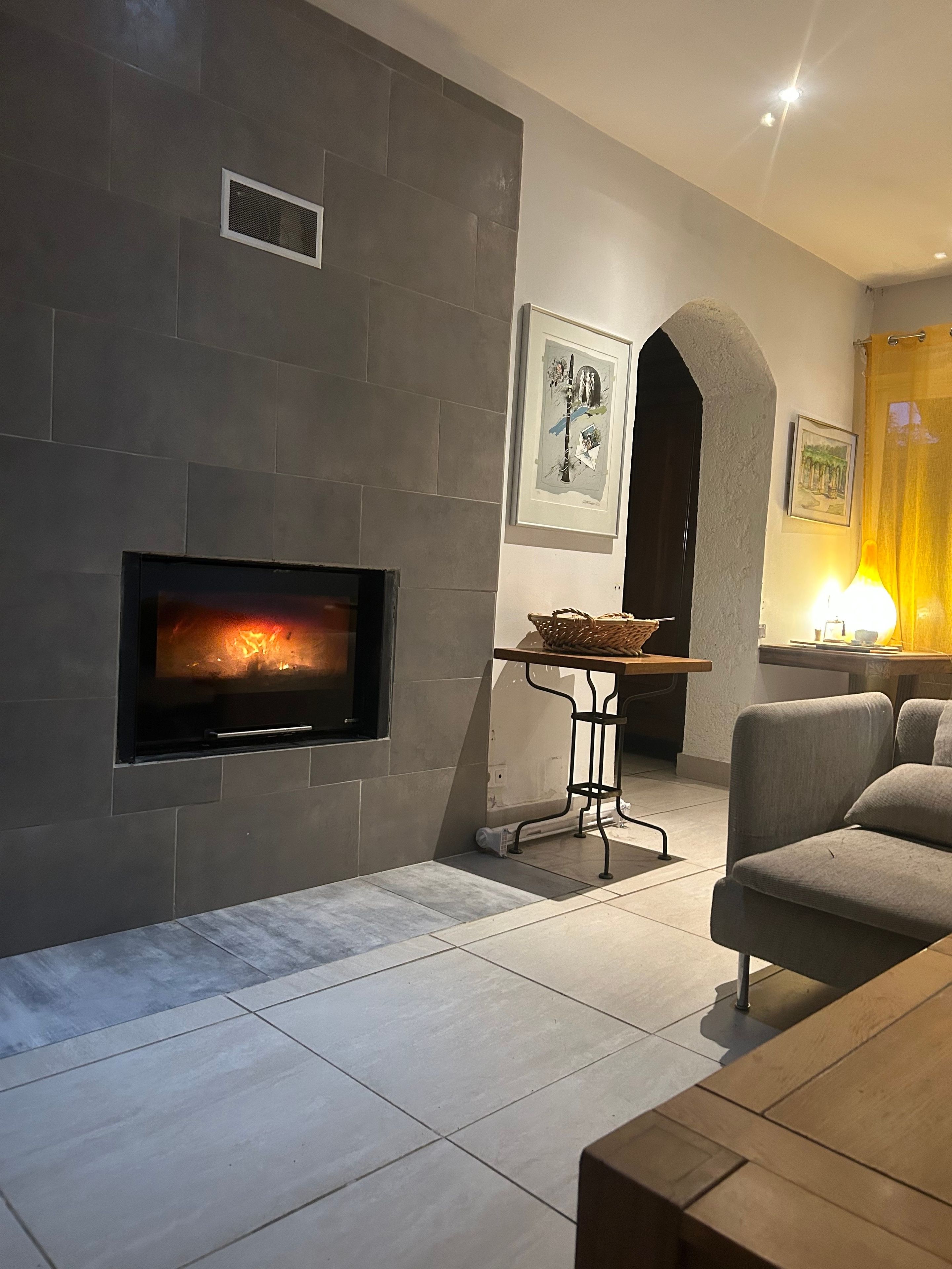 A modern living room with a fireplace, a sofa, a coffee table, and a dining area.