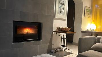 A modern living room with a fireplace, a sofa, a coffee table, and a dining area.
