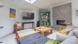A modern living room with a skylight, a flat-screen TV, a bookshelf, a fireplace, and a sofa.