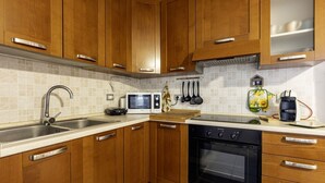 A kitchen with wooden cabinets, a stainless steel sink, a microwave, an oven, and various kitchen utensils. - GuestHost - Charming apartment of about 65 sqm, perfect for up to 4 guests, located on the third floor of a building with an elevator (NOT for disabled people.)The property is located in Quartu Sant’Elena, in a residential area well served by main amen (Quartu Sant'Elena)