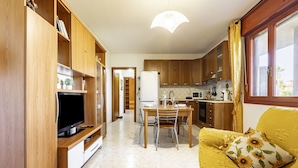 A compact living space with a dining area, kitchenette, and a television on a wooden stand. - GuestHost - Charming apartment of about 65 sqm, perfect for up to 4 guests, located on the third floor of a building with an elevator (NOT for disabled people.)The property is located in Quartu Sant’Elena, in a residential area well served by main amen (Quartu Sant'Elena)