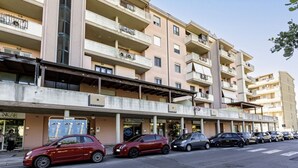 A multi-story residential building with balconies, a parking area, and a sign for 'Nicar.' - GuestHost - Charming apartment of about 65 sqm, perfect for up to 4 guests, located on the third floor of a building with an elevator (NOT for disabled people.)The property is located in Quartu Sant’Elena, in a residential area well served by main amen (Quartu Sant'Elena)