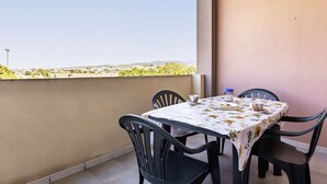 A balcony with a table set for two, chairs, and a view of a distant landscape. - GuestHost - Charming apartment of about 65 sqm, perfect for up to 4 guests, located on the third floor of a building with an elevator (NOT for disabled people.)The property is located in Quartu Sant’Elena, in a residential area well served by main amen (Quartu Sant'Elena)