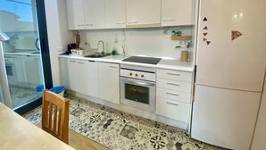 Eine moderne Küche mit weißen Schränken, einem Backofen und einem Kühlschrank.