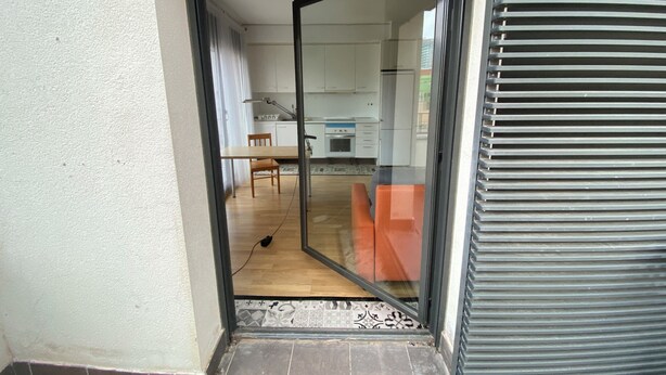 Eine moderne Küche mit weißen Schränken, einem Holzespeisetisch und einem roten Sofa.
