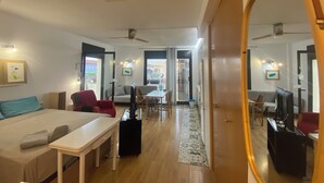Ein modernes Hotelzimmer mit Bett, Schreibtisch, Fernseher und einer Essecke mit Stühlen und Tisch.