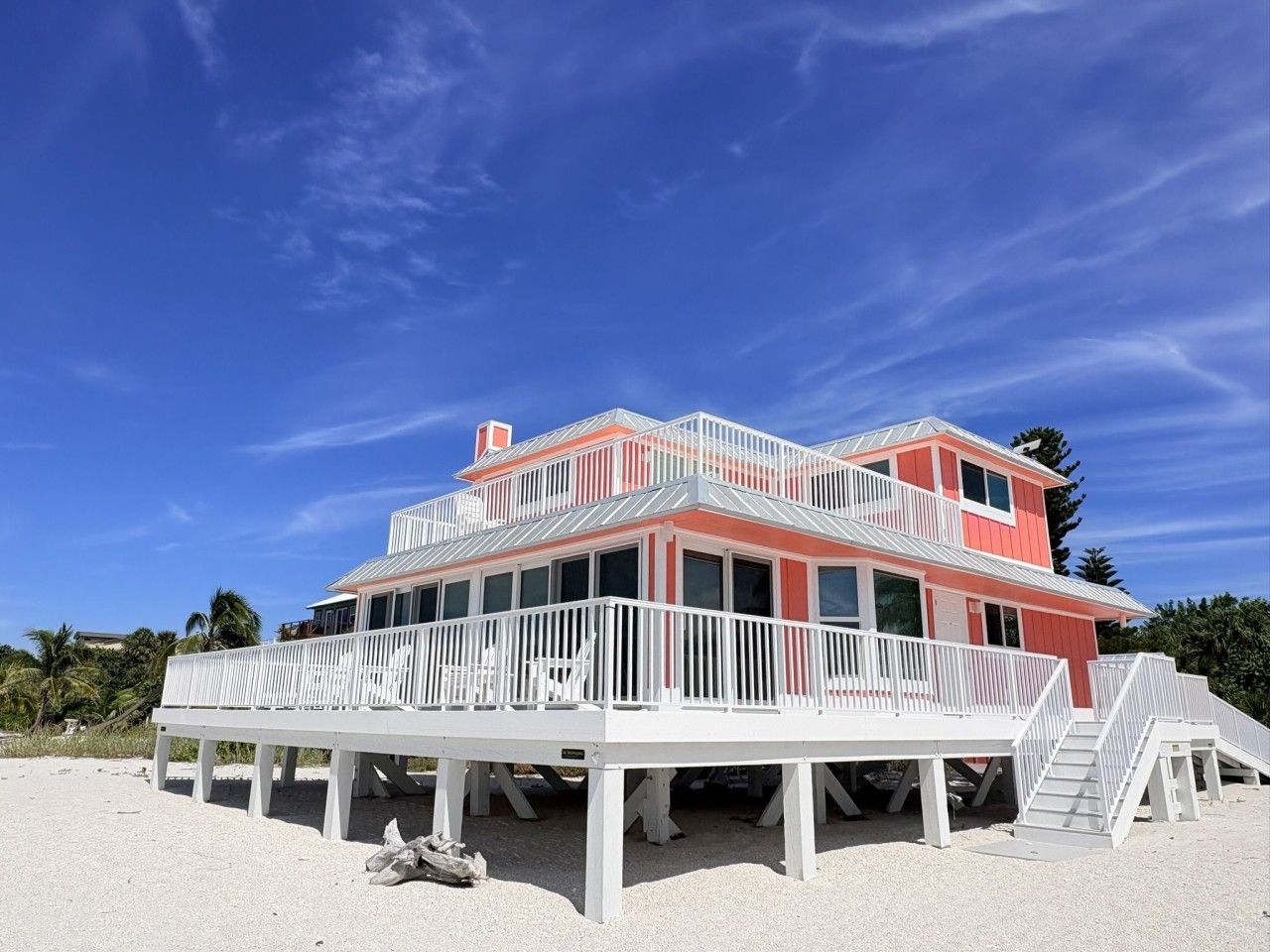A two-story beach house with a balcony and a staircase leading to the upper level.