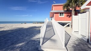 Un paseo marítimo que conduce a un edificio de fachada roja y una palmera.