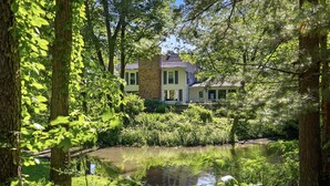 A house surrounded by lush greenery and a pond. - Juniper Presents: The Loft at Historic 33 Acre Berrywood Farm (Three Oaks)