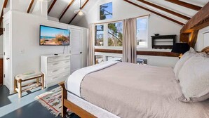 A bedroom with a bed, a TV, a window, and a wooden ceiling structure. - Juniper Presents: The Loft at Historic 33 Acre Berrywood Farm (Three Oaks)