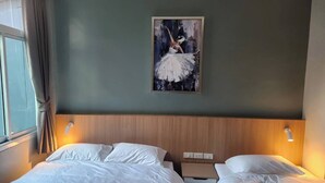 A hotel room with two beds, a wooden headboard, a painting of a ballerina, and a window with curtains. - Wan Residence Ratchatewi  (Bangkok)