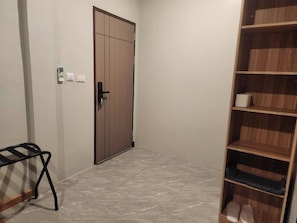 A hallway with a wooden door, a black metal bench, and a wooden shelving unit with shelves. - Wan Residence Ratchatewi  (Bangkok)
