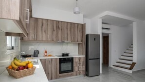 Eine moderne Küche mit Holzausstattung, einem Edelstahlkühlschrank und einer Obstschale auf der Arbeitsfläche.