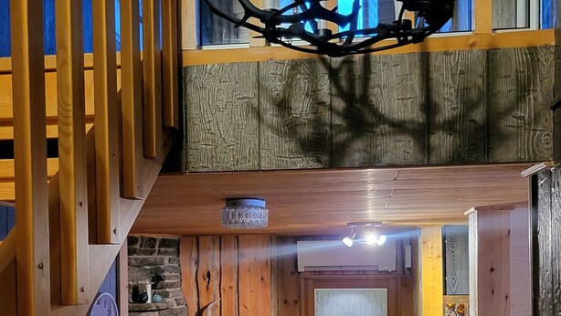 Um interior rústico de madeira com lareira de pedra, um relógio e um candelabro.