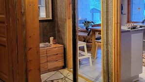 Quarto com piso de ladrilho de pedra, paredes de madeira, um espelho grande e vista para o exterior.