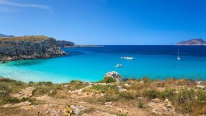 Un paisaje costero con aguas turquesas cristalinas, acantilados rocosos y una isla distante.