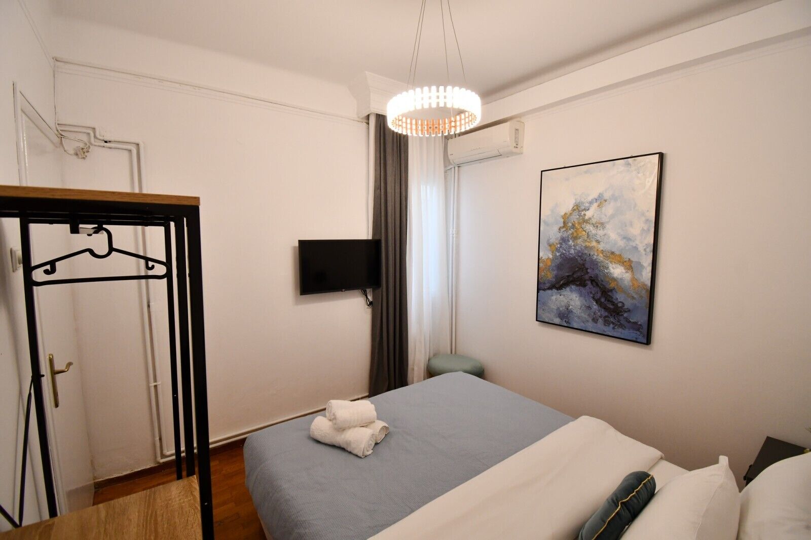 Ett hotellrum med en säng, en tv, en tavla och en garderob.